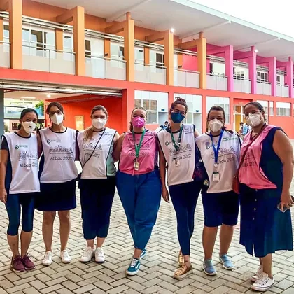 Sete estudantes de colete em frente a um prédio colorido