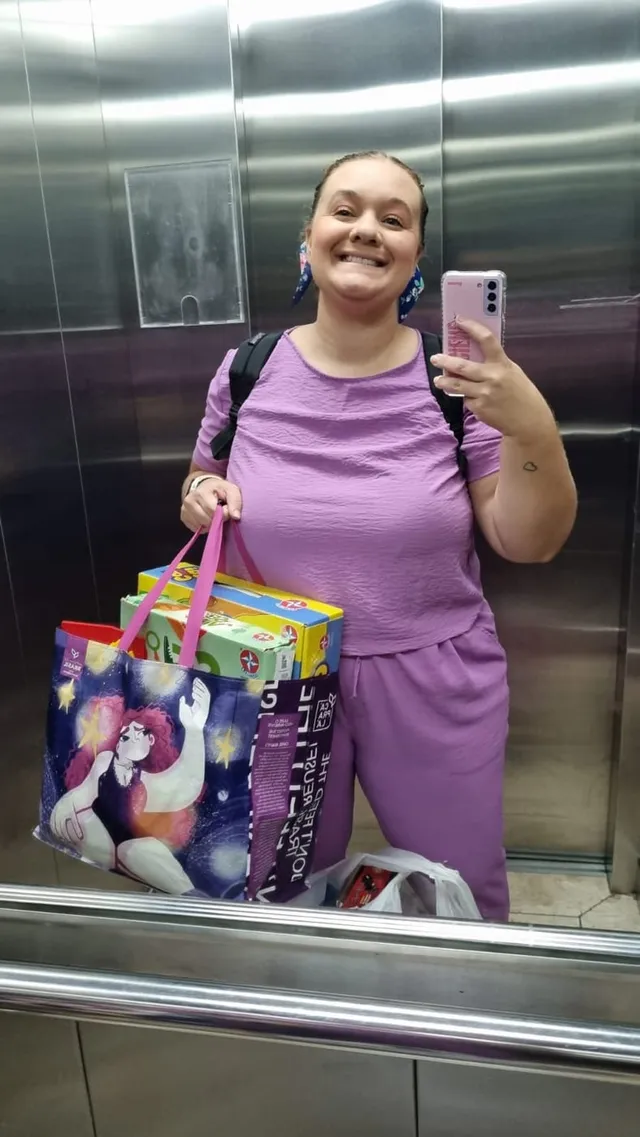 Luciene no elevador, carregando uma sacola com jogos de terapia