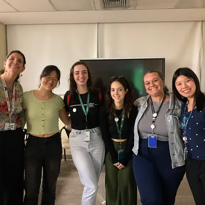 Seis mulheres com crachás em uma sala de reunião