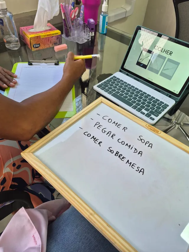 Mesa de terapia com tablet e quadro com frases escritas